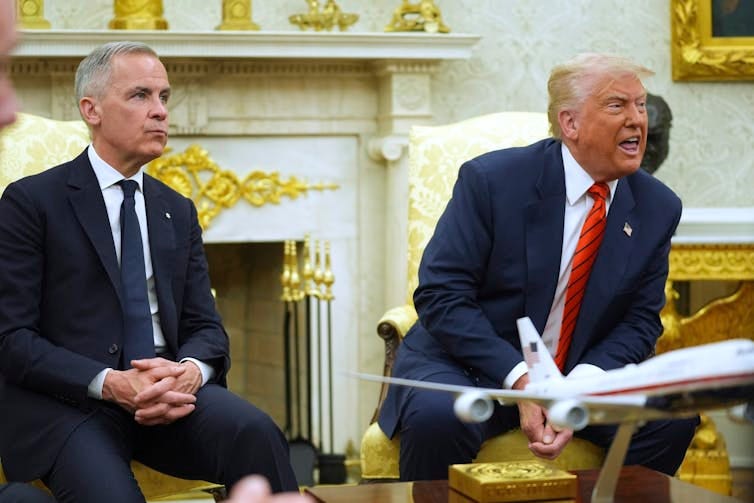 A man with short grey hair sits next to a rotund man with fluffy white-blond hair who's sneering as he answers reporters who are not seen in the photos. A man with short grey hair sits next to a rotund man with fluffy white-blond hair who's sneering as he answers reporters who are not seen in the photos.