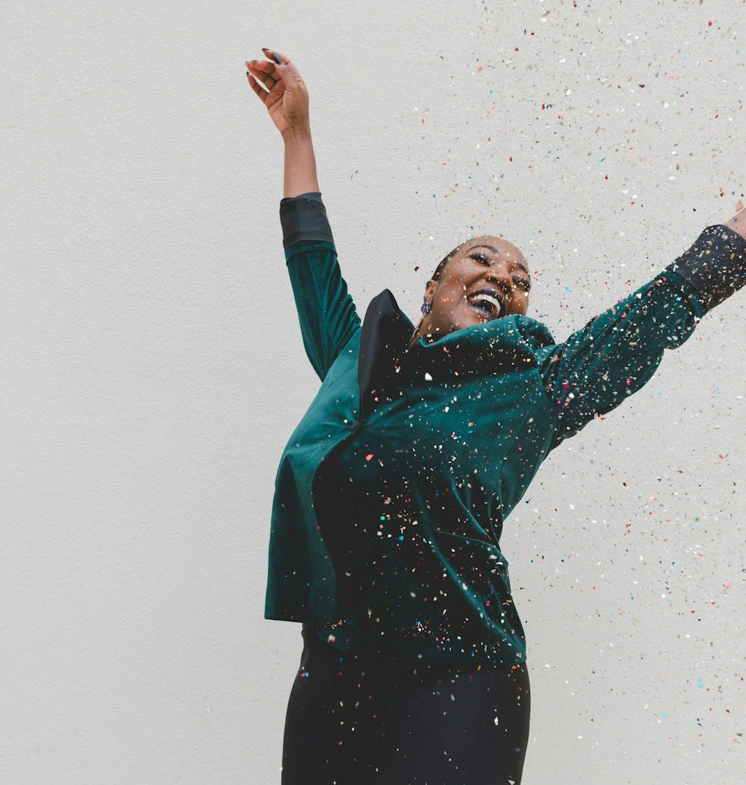 woman in green jacket raising her hands