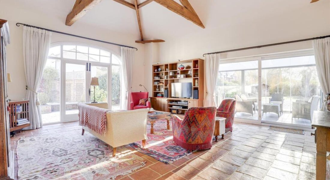 A living room with white walls, wooden beams, sofas and rugs, and stone flooring A living room with white walls, wooden beams, sofas and rugs, and stone flooring