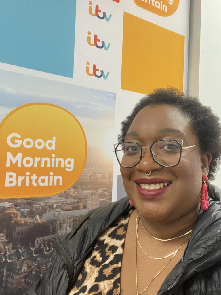 Tinuke Bernard smiling in front of the Good Morning Britain signs