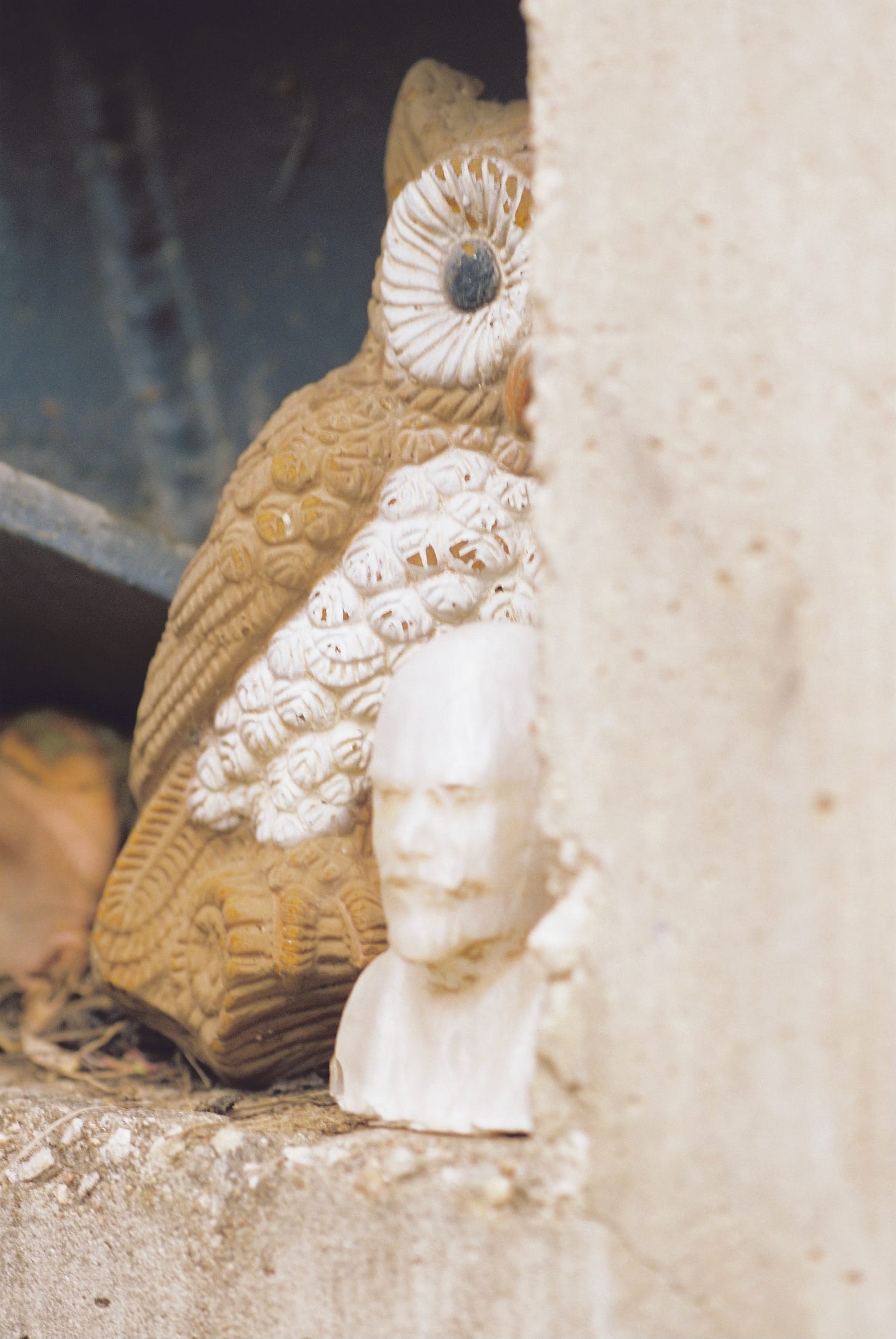 3-D-printed bust of Lenin and plaster owl wall hanging sitting on an outdoor shelf