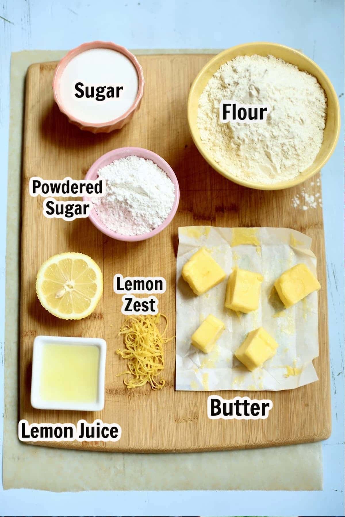a wooden cutting board with several ingredents to make shortbread, with text overlay saying what each ingredient is.