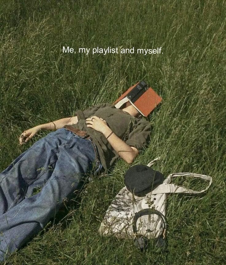 This may contain: a person laying in the grass with a book This may contain: a person laying in the grass with a book