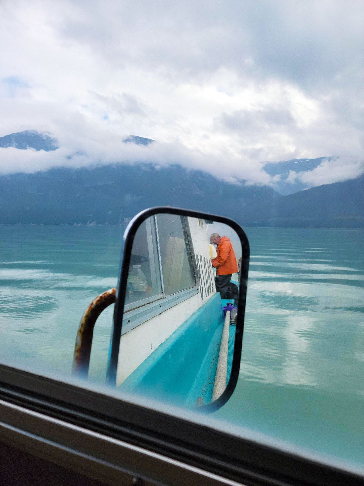 Hank Shaw cleaning salmon in the rearview mirror of the boat.