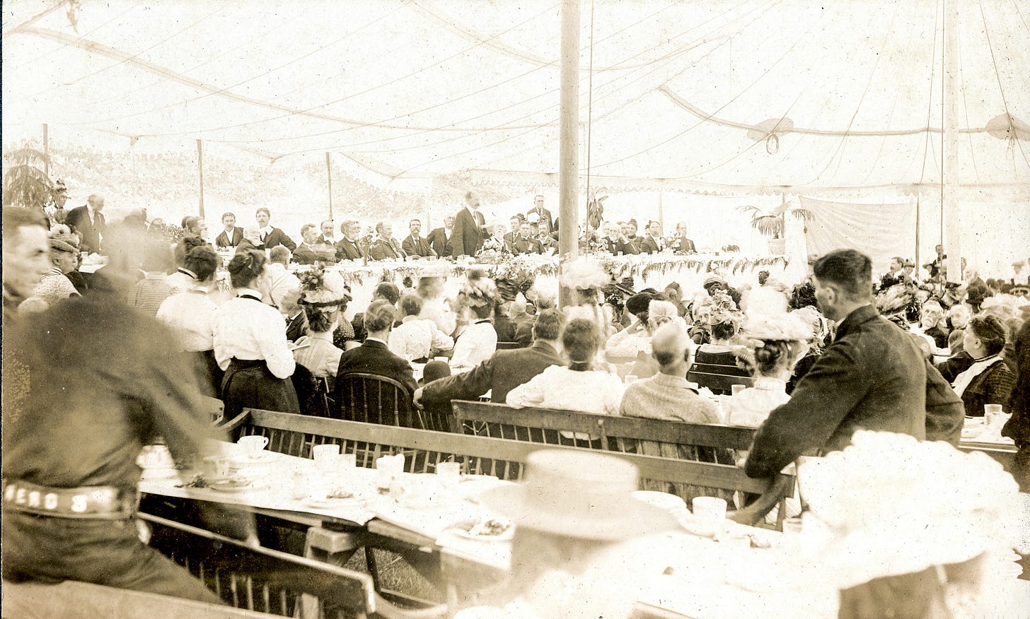 Group of people under tent, listening to speakers