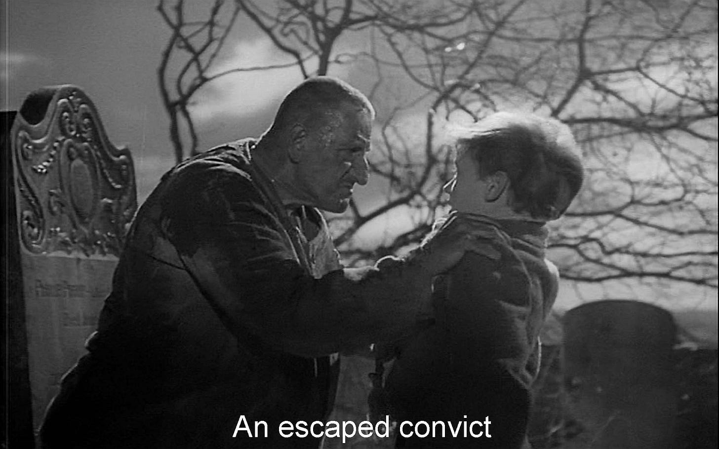 b/w photo from 1946 film; rough man grabs small scared boy by lapels in a graveyard. 