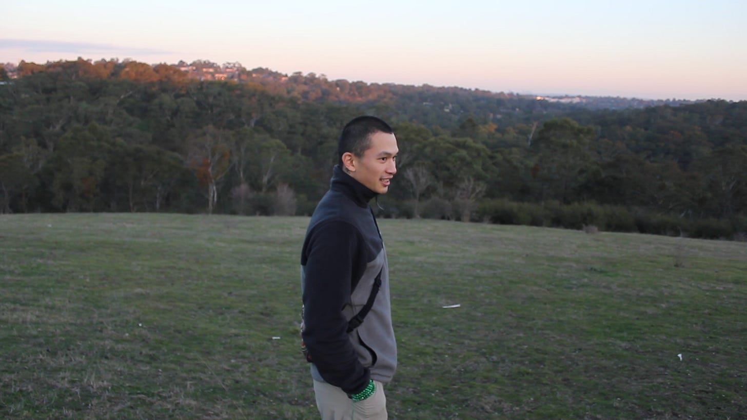 Peaceful hiking scene with a single figure surrounded by rolling hills and open sky.