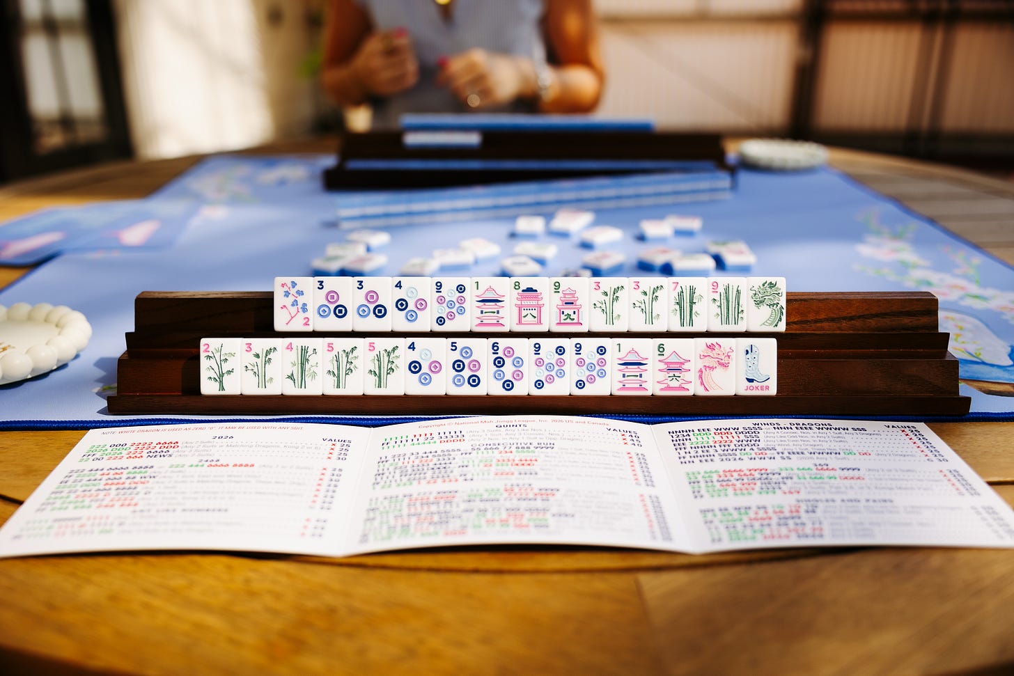 Two rows of mahjong tiles on a wooden Siamese rack, with the card open on the table. Two rows of mahjong tiles on a wooden Siamese rack, with the card open on the table.