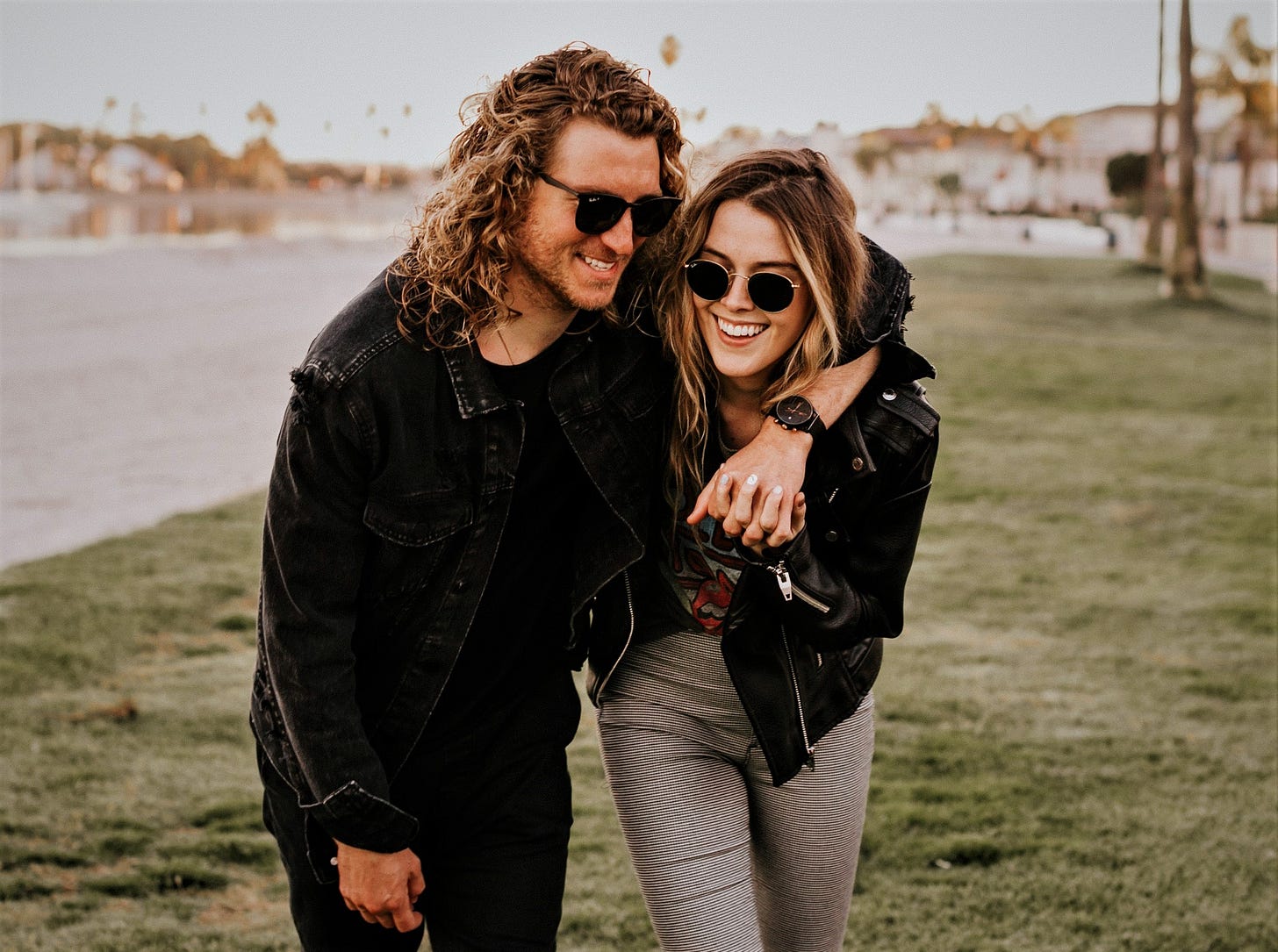 happy couple walking along lake holding hands