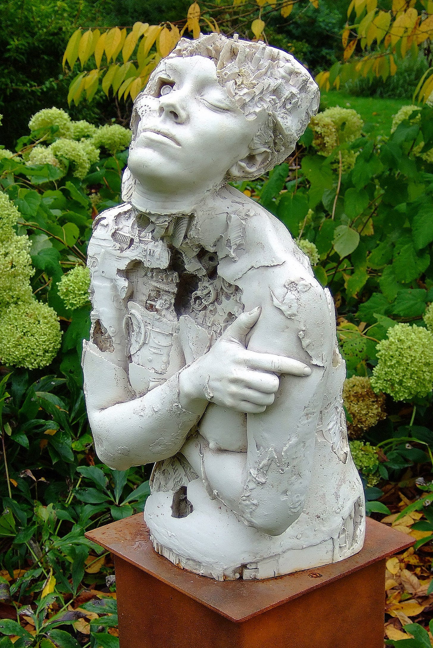 A photograph of a marble resin sculpture of a cyborg mounted on a simple wooden plinth stood in a garden setting. The concepts of time and discovery are intended to be portrayed in this sculptural work. Machine made objects creating mechanical textures have been fused with a human form cast from life. The skin has eroded in areas to reveal mechanical systems analogous to the internal workings of the body. A photograph of a marble resin sculpture of a cyborg mounted on a simple wooden plinth stood in a garden setting. The concepts of time and discovery are intended to be portrayed in this sculptural work. Machine made objects creating mechanical textures have been fused with a human form cast from life. The skin has eroded in areas to reveal mechanical systems analogous to the internal workings of the body.