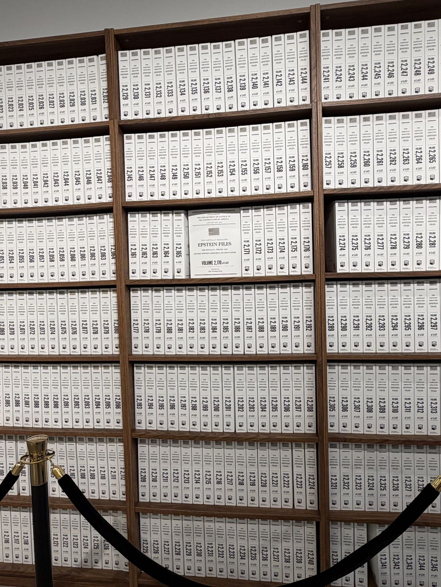 a series of book shelf filled white binders, behind a rope