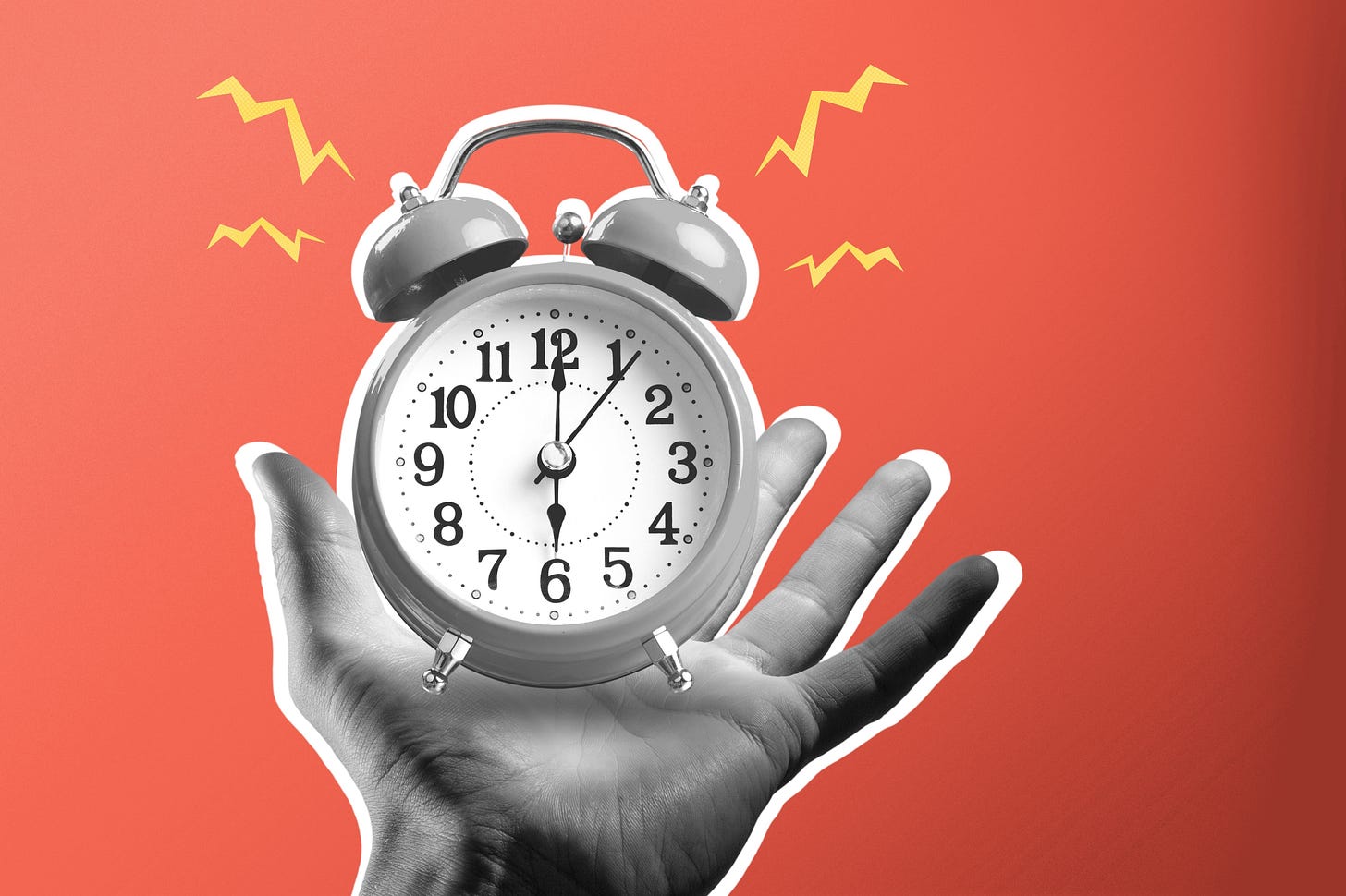 A hand holding a ringing alarm clock