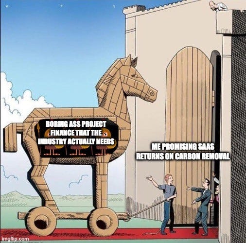 Cartoon of a wooden Trojan horse wheeled toward a castle gate. Label on the horse: "BORING ASS PROJECT FINANCE THAT THE INDUSTRY ACTUALLY NEEDS". Label on the man leading it in: "ME PROMISING SAAS RETURNS ON CARBON REMOVAL"
