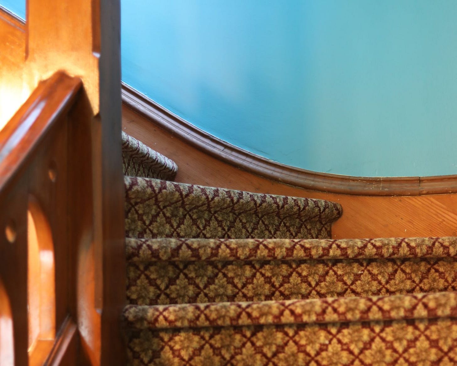 A close-up view of the turn of a stairway in an 1889 house, the steps are wedge-shaped at the turn.