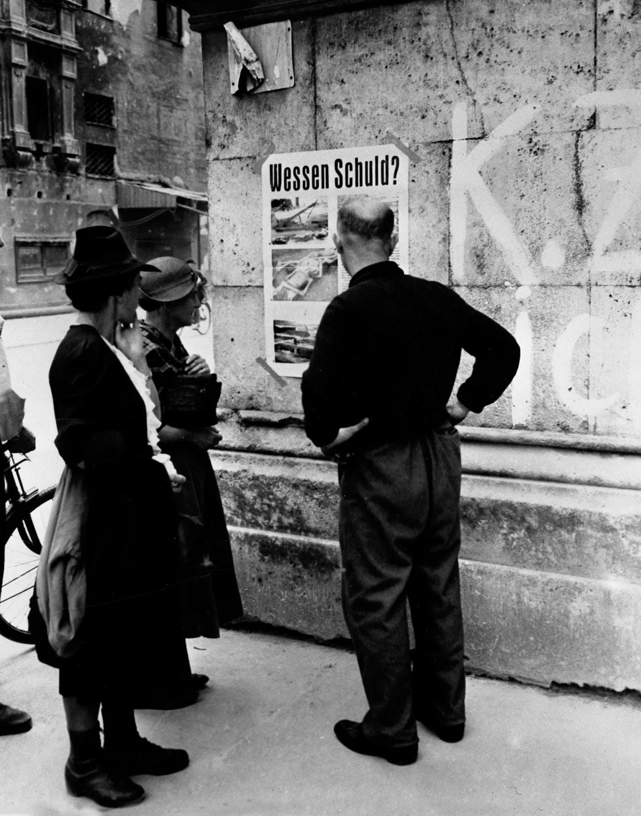 "Whose Fault?" A poster with photos of German concentration camp atrocities being publicly displayed for Germans in Munich, US occupied Germany, 1945