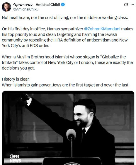 A black and white photograph of a man speaking into a microphone with a serious expression, conveying a strong political message.