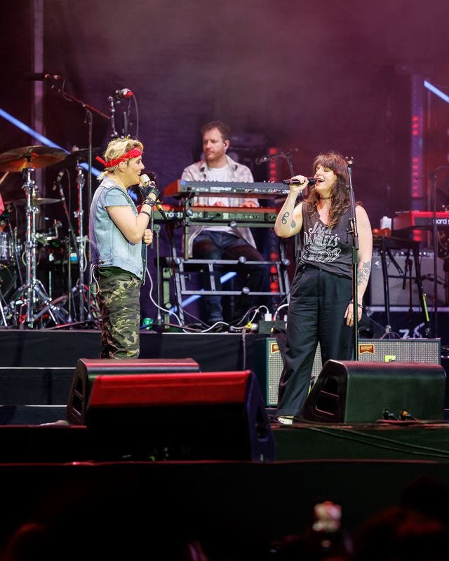 Megan Falley and Brandi Carlile on stage, signing to each other with microphones in hand.