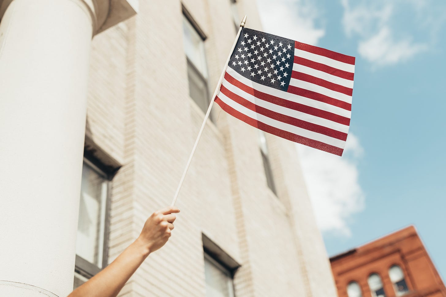 Hand holding a small american flag on a stick