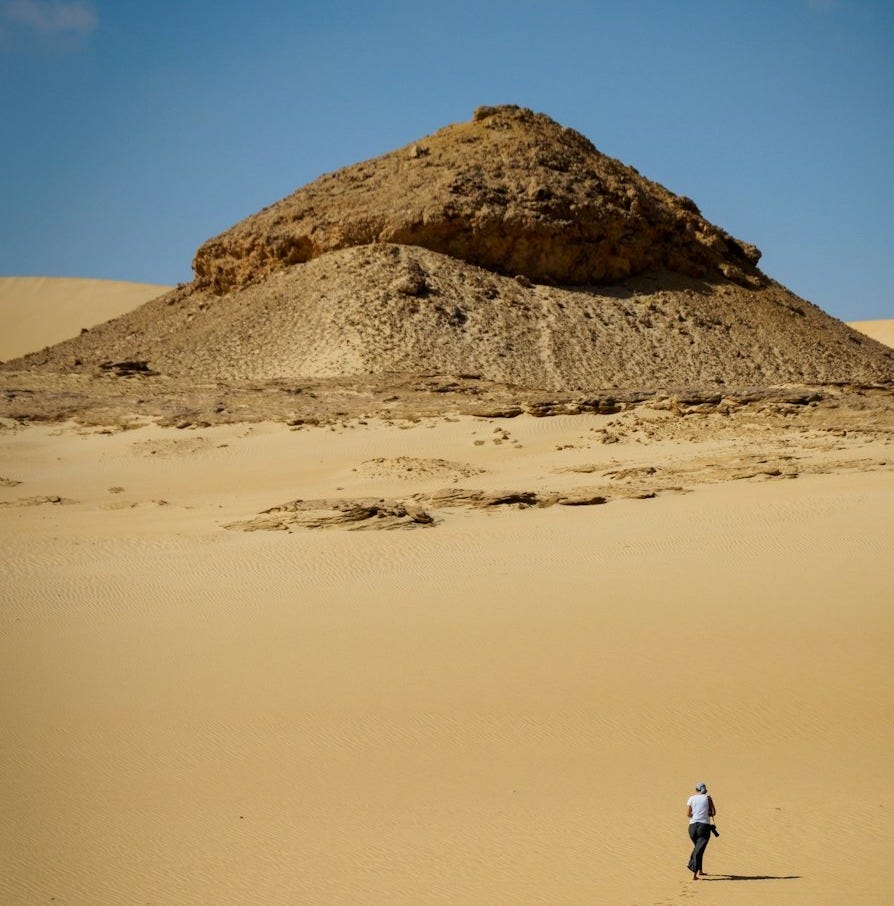 man in white shirt walking on brown sand during daytime