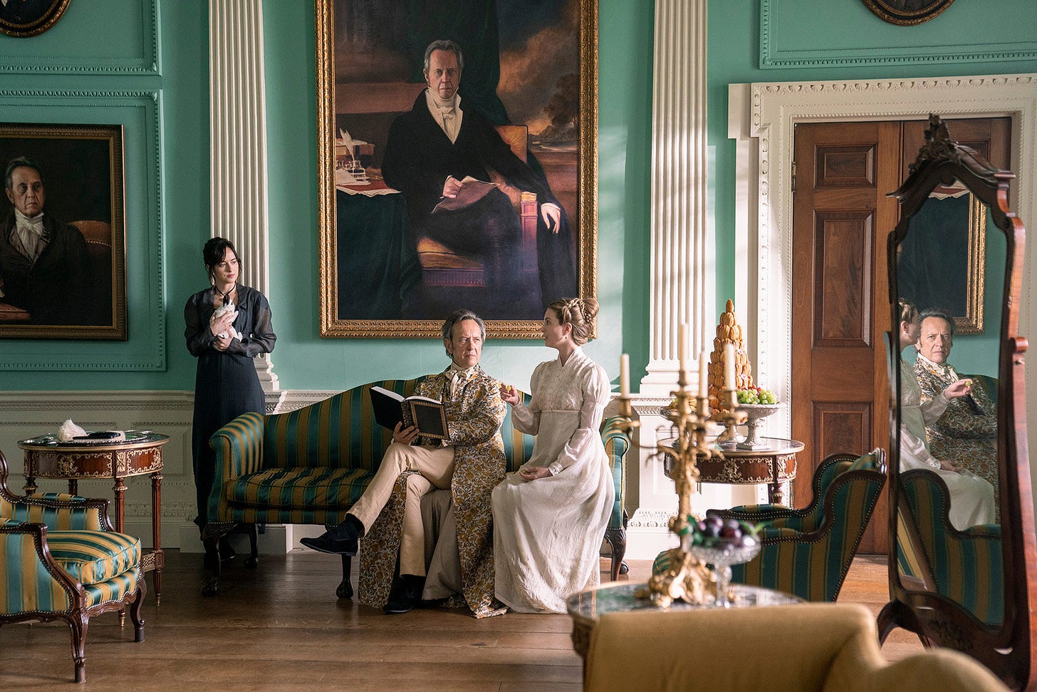 Sir Walter and Elizabeth are sitting on a sofa. Anne stands behind them and is holding a rabbit. Sir Walter and Elizabeth are sitting on a sofa. Anne stands behind them and is holding a rabbit.