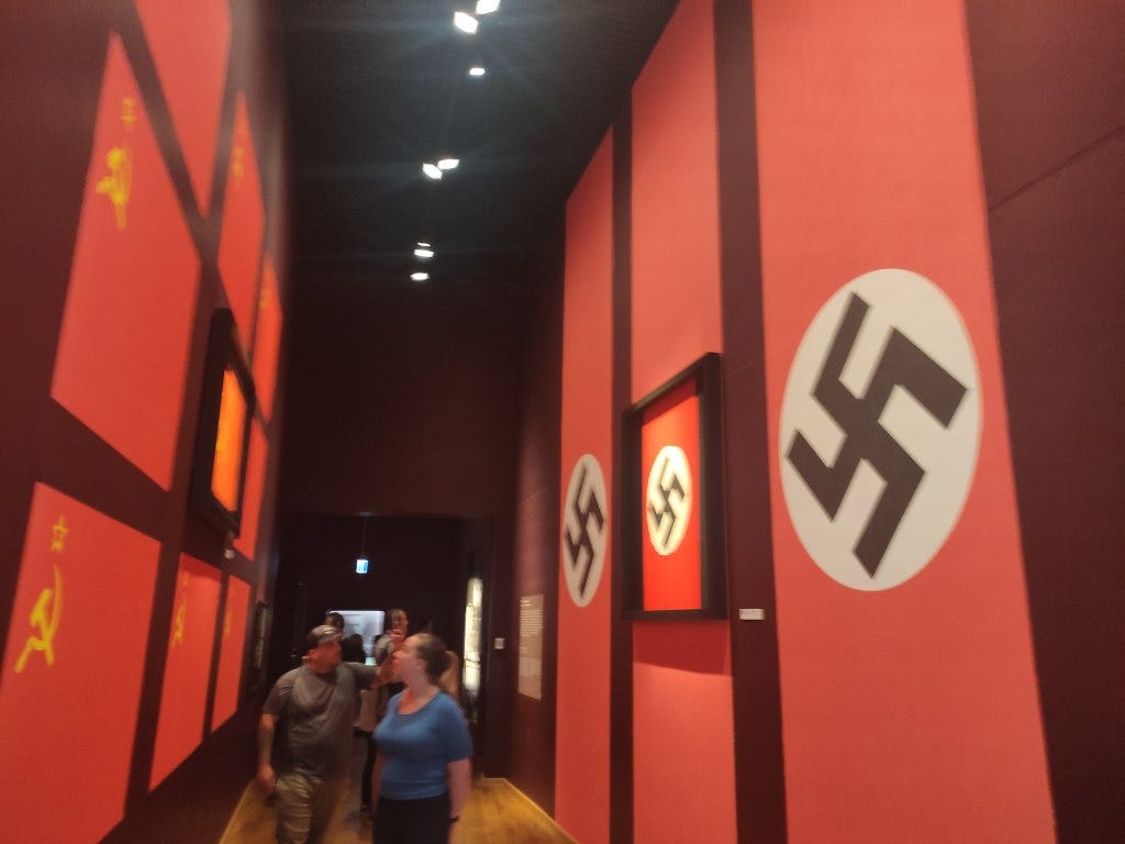 A corridor lined with Nazi swastikas and Soviet sickles sets a tone