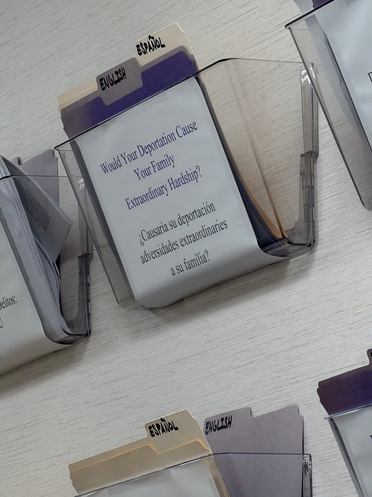 A plastic file holder screwed to the wall with a paper on it saying : would your deportation cause your family extraordinary hardship A plastic file holder screwed to the wall with a paper on it saying : would your deportation cause your family extraordinary hardship