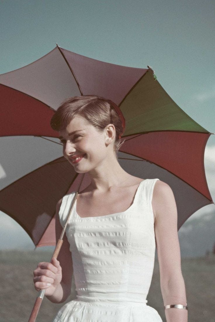 This may contain: a woman in a white dress holding an umbrella