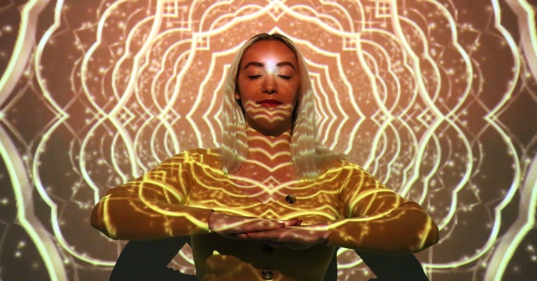 a woman in a yellow outfit is standing in front of a glowing background