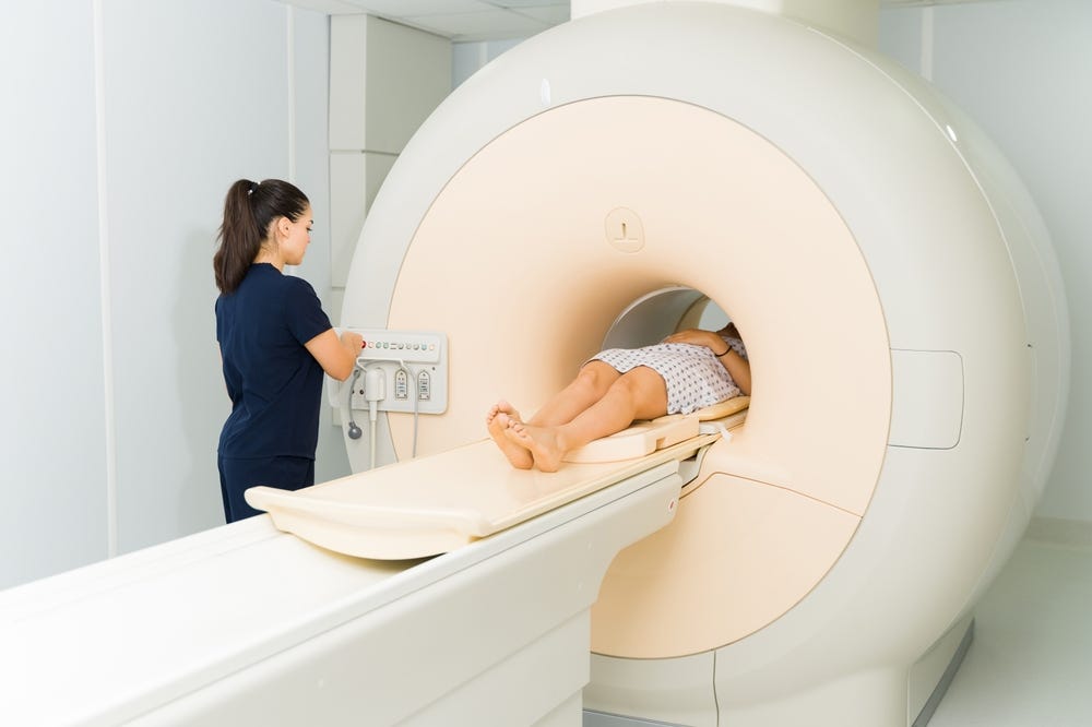 MRI machine with patient and tech person.