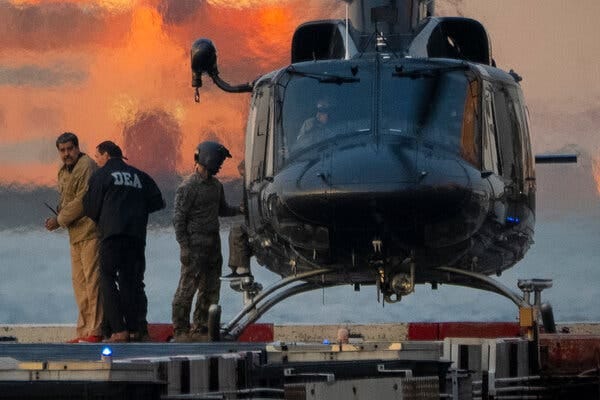 Nicolás Maduro junto a un hombre con una chaqueta de la DEA cerca de un helicóptero.