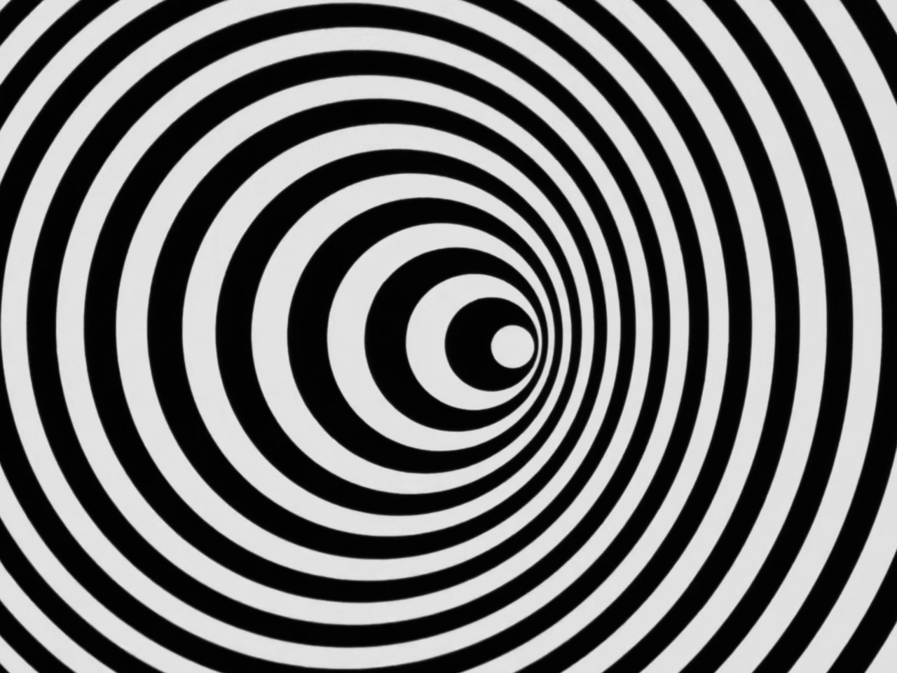 A black and white image featuring a series of nested, horizontally offset, alternating black and white circular bands that converge toward a slightly off-center white disc. The arrangement creates a tunnel-like or vortex effect, producing a strong illusion of depth and motion. A black and white image featuring a series of nested, horizontally offset, alternating black and white circular bands that converge toward a slightly off-center white disc. The arrangement creates a tunnel-like or vortex effect, producing a strong illusion of depth and motion.