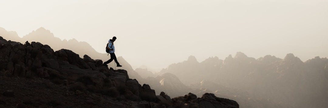 a man running up a mountain with a sky background