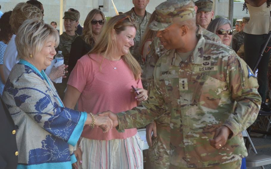 Army officer shakes hands with a woman in a crowd of people. Army officer shakes hands with a woman in a crowd of people.