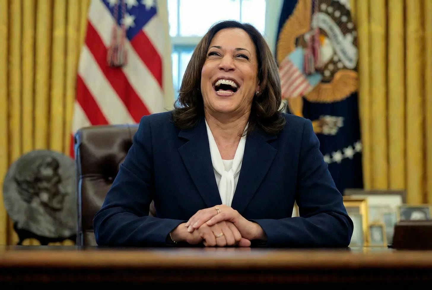 Kamala Harris sitting at the Oval Office desk, laughing. Kamala Harris sitting at the Oval Office desk, laughing.