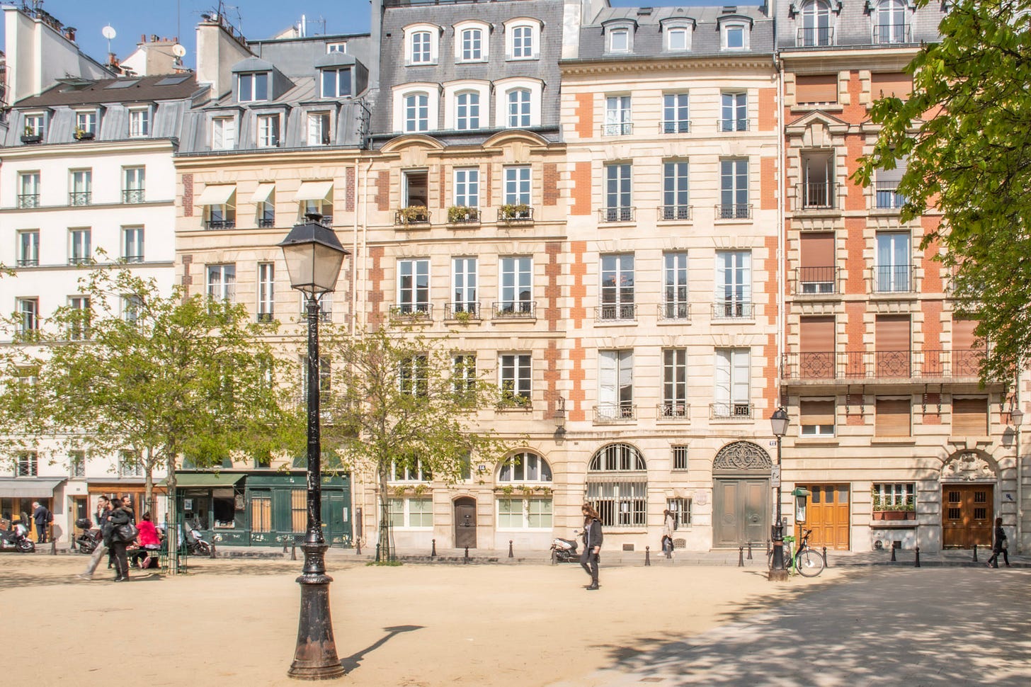 Classic Parisian buildings and trees surrounding Place Dauphine on Île de la Cité