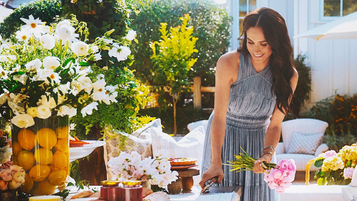 a smiling woman holds a bunch of flowers on a sunny outdoor patio