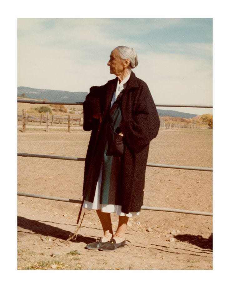 This may contain: an old woman standing in front of a fence