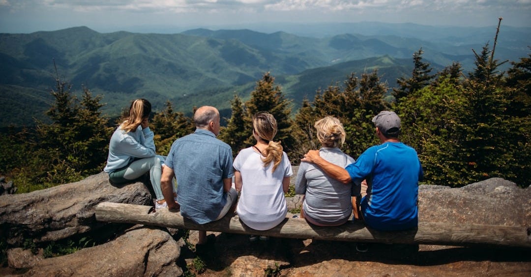 group of people sitting on rocks overlooking mountain