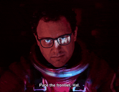 A man in an astronaut suit and glasses stares forward under red and blue lighting; subtitle reads Pace the frontier, Hal.