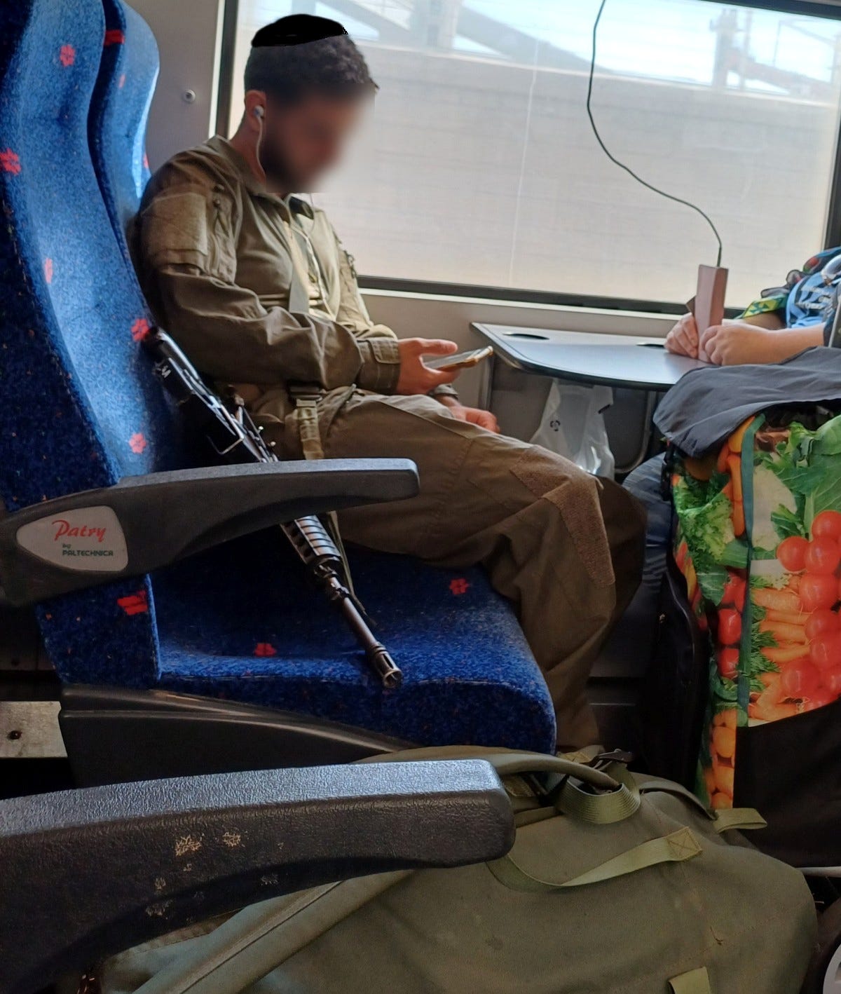 Soldier on Israeli train with his weapon and duffel bag
