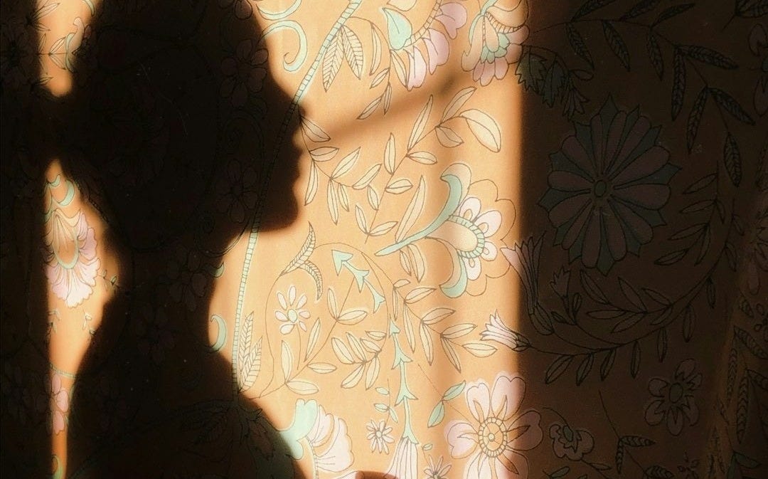 woman in black shirt standing near white and brown floral curtain