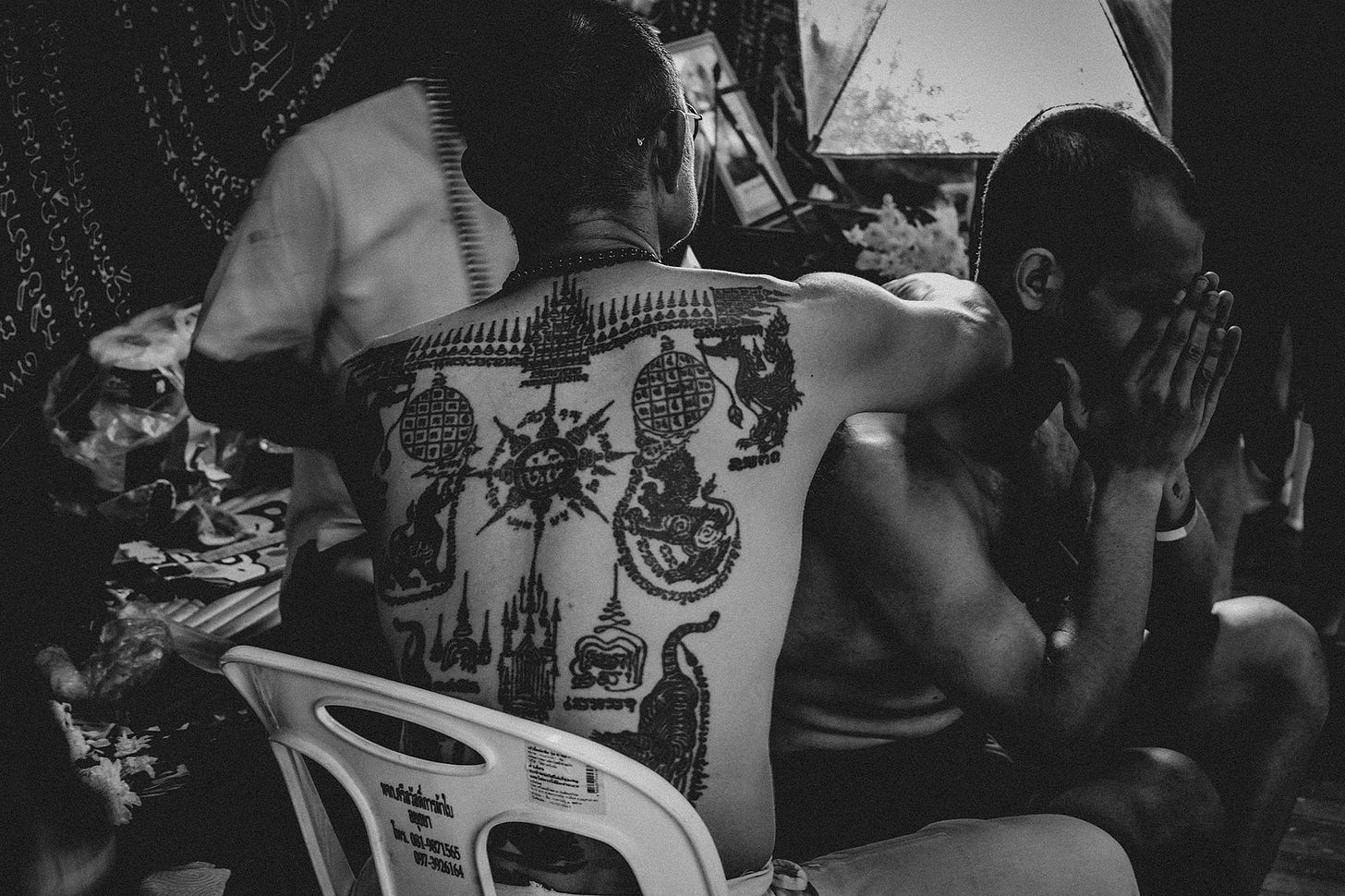Um ex-monge tatua um viajante estrangeiro durante o 17º World Wai Khru Muay Thai na cidade histórica de Ayutthaya, na Tailândia.