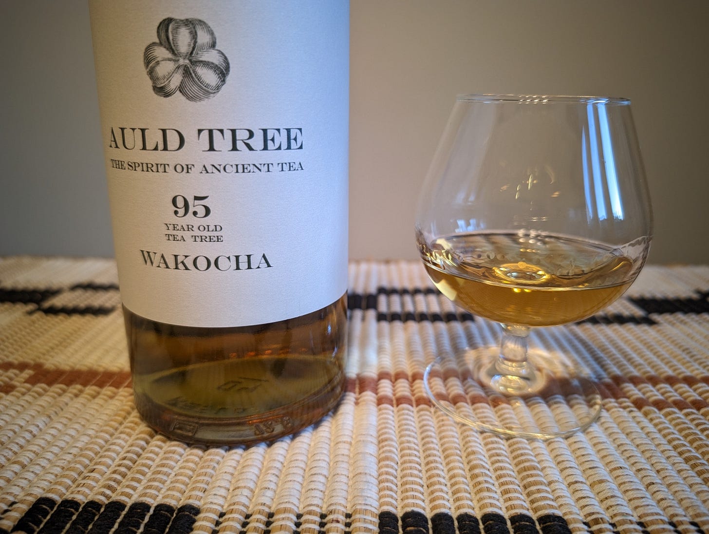 a bottle of whiskey next to a brandy snifter, containing said whiskey