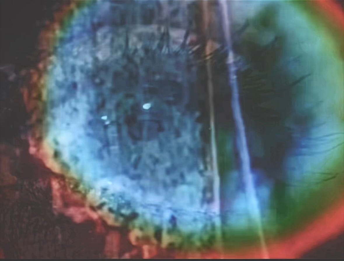 picture of an eye with long eyelashes and a rainbow color prism around the eye