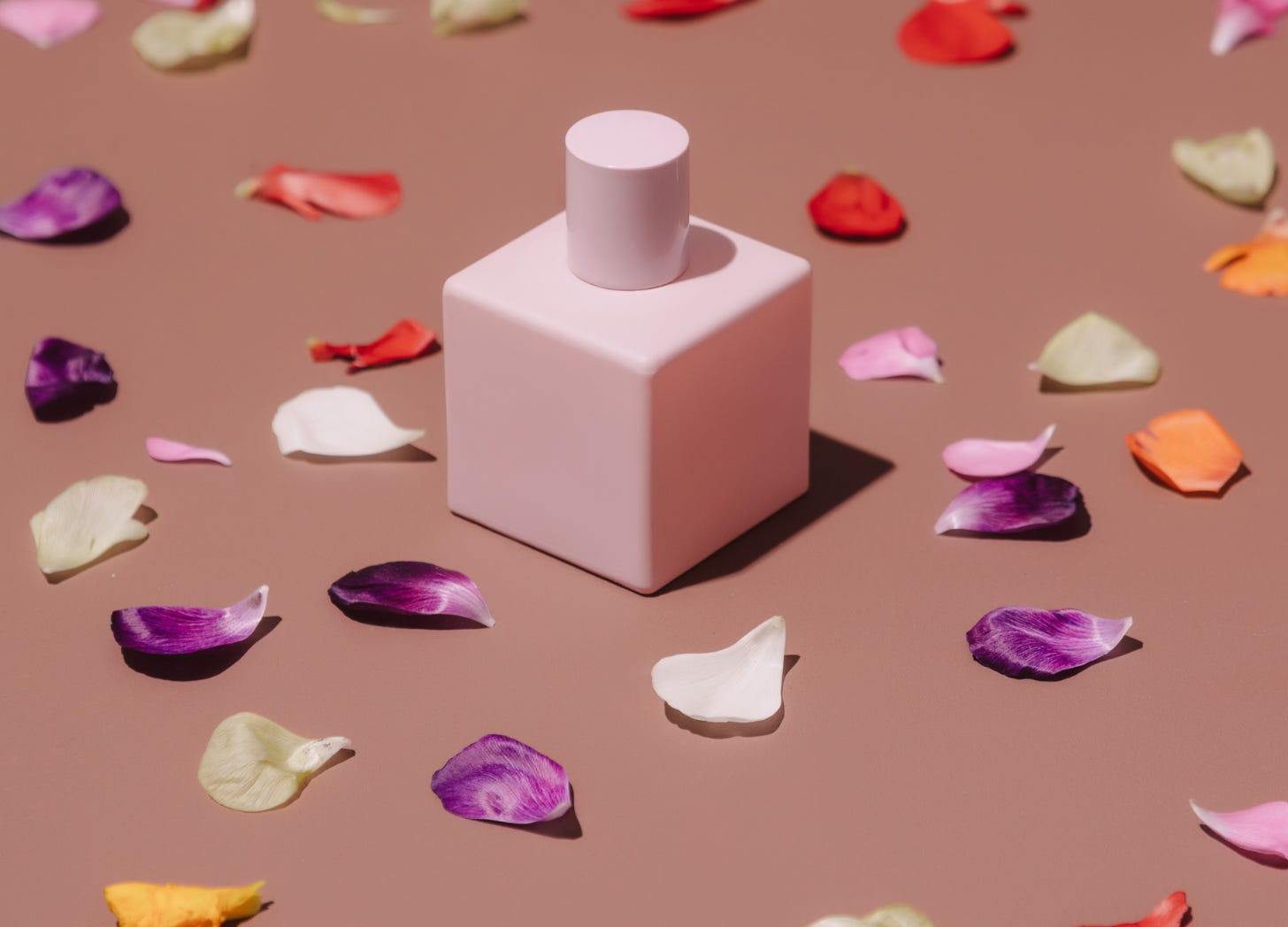Bottle of perfume with petals around it