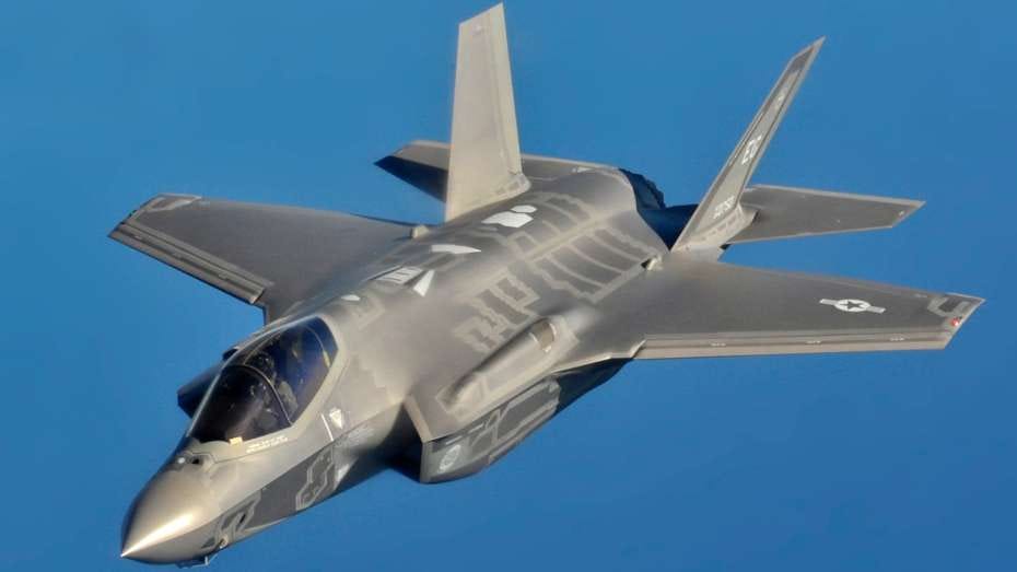 An American Lockheed Martin F-35 stealth fighter flies in a clear, blue sky.