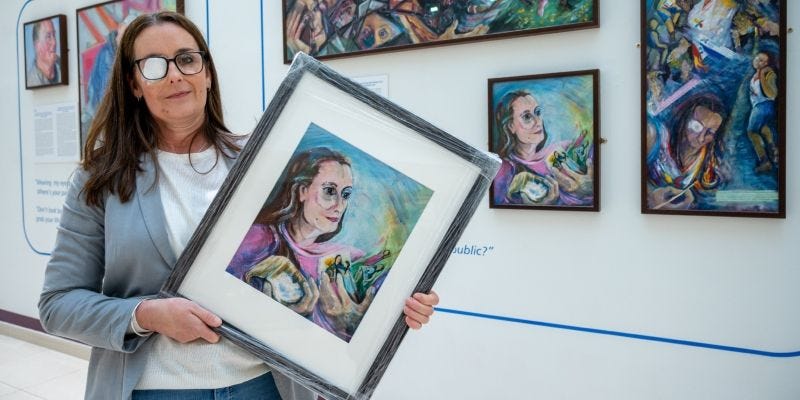 Rebecca holds her painting in front of the I'm Still Me exhibition Rebecca holds her painting in front of the I'm Still Me exhibition