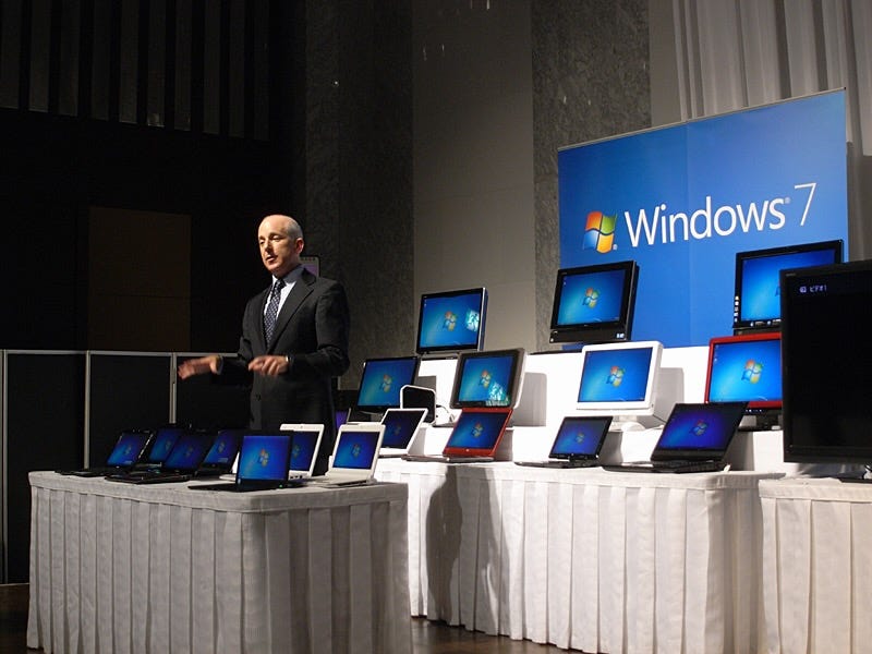 Photo of me in a suit with several rows of Windows 7 PCs on display and a sign that says Windows 7. Photo of me in a suit with several rows of Windows 7 PCs on display and a sign that says Windows 7.
