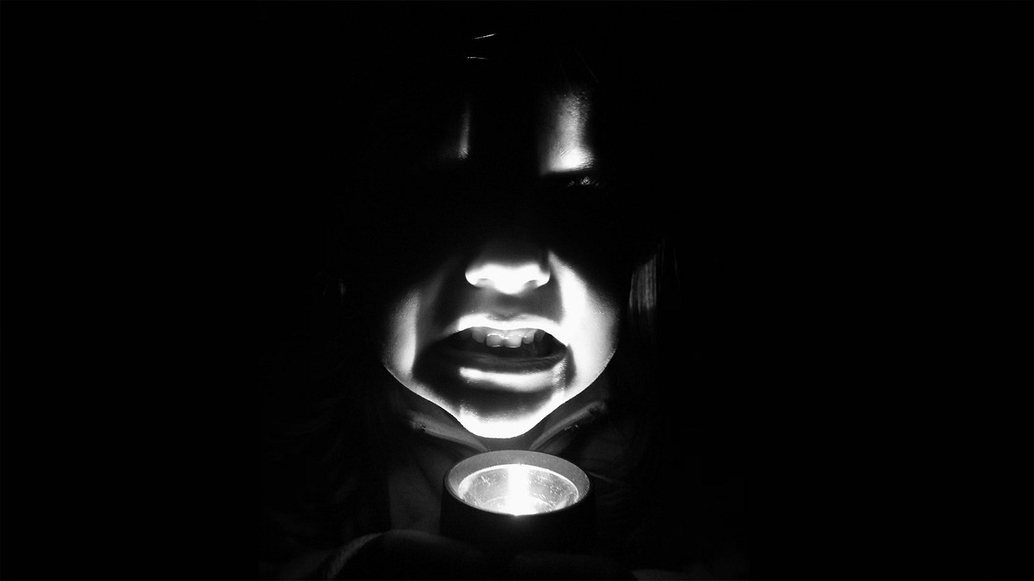 Man holding a flashlight under his chin