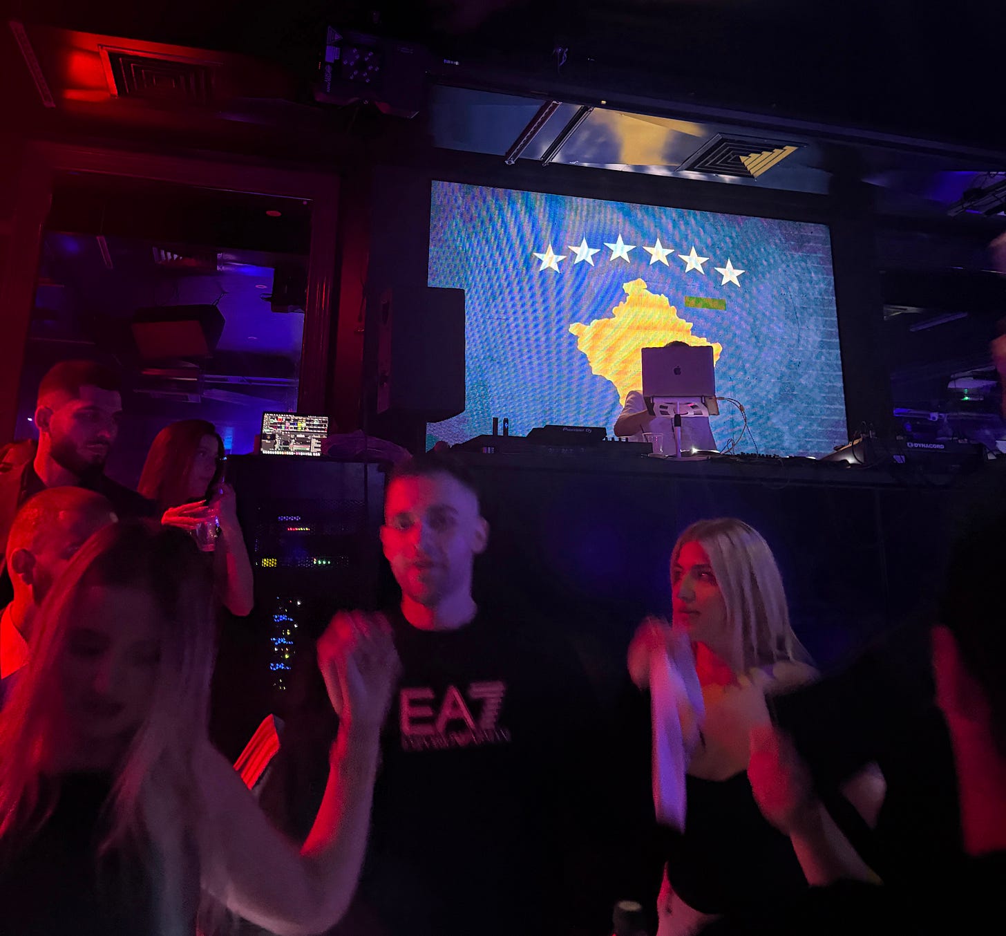 Strangers holding hands and dancing Valle in the Balkan club, with flags of different Eastern European countries being put on screen. Strangers holding hands and dancing Valle in the Balkan club, with flags of different Eastern European countries being put on screen.